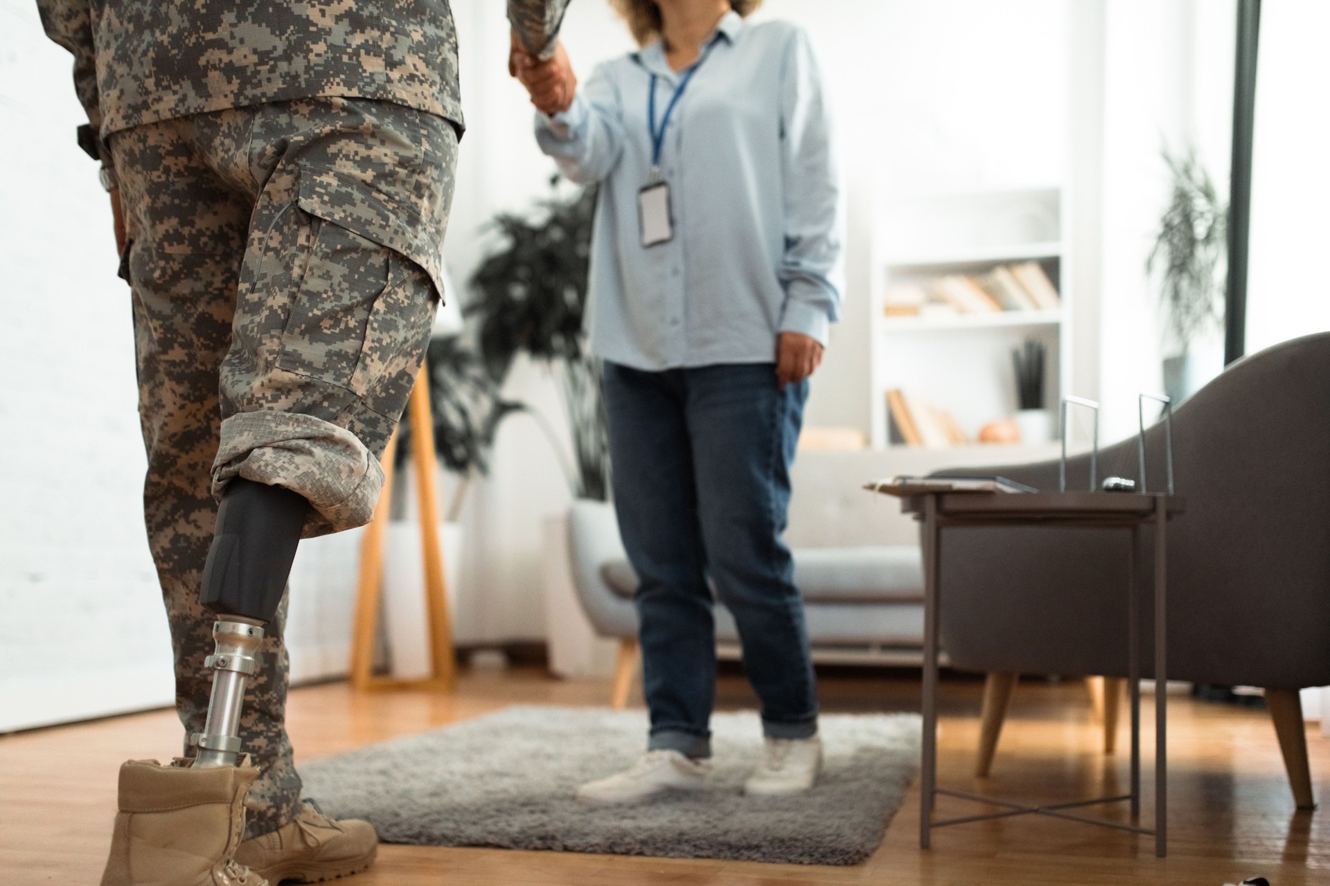 Therapist and veteran with a prosthetic leg in therapy room shaking hands